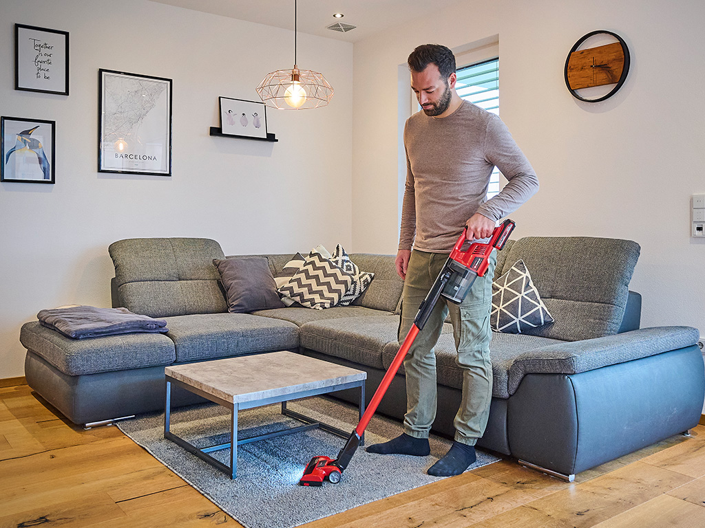 A man vacuuming the floor with the cordless vacuum. 