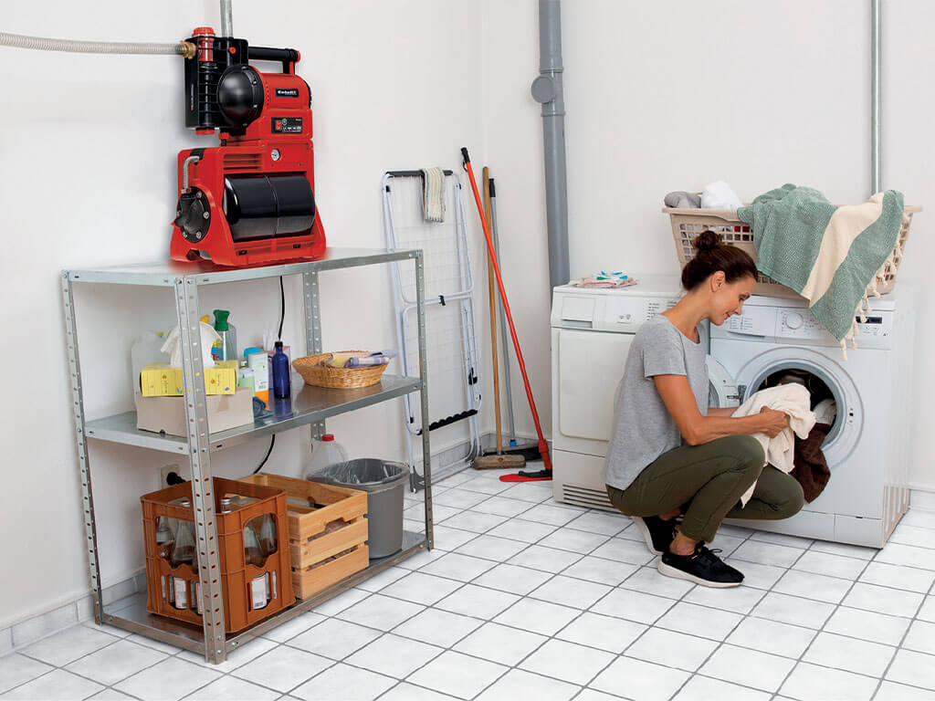 A woman fills her washing machine, which is supplied with water by an Einhell domestic waterworks.