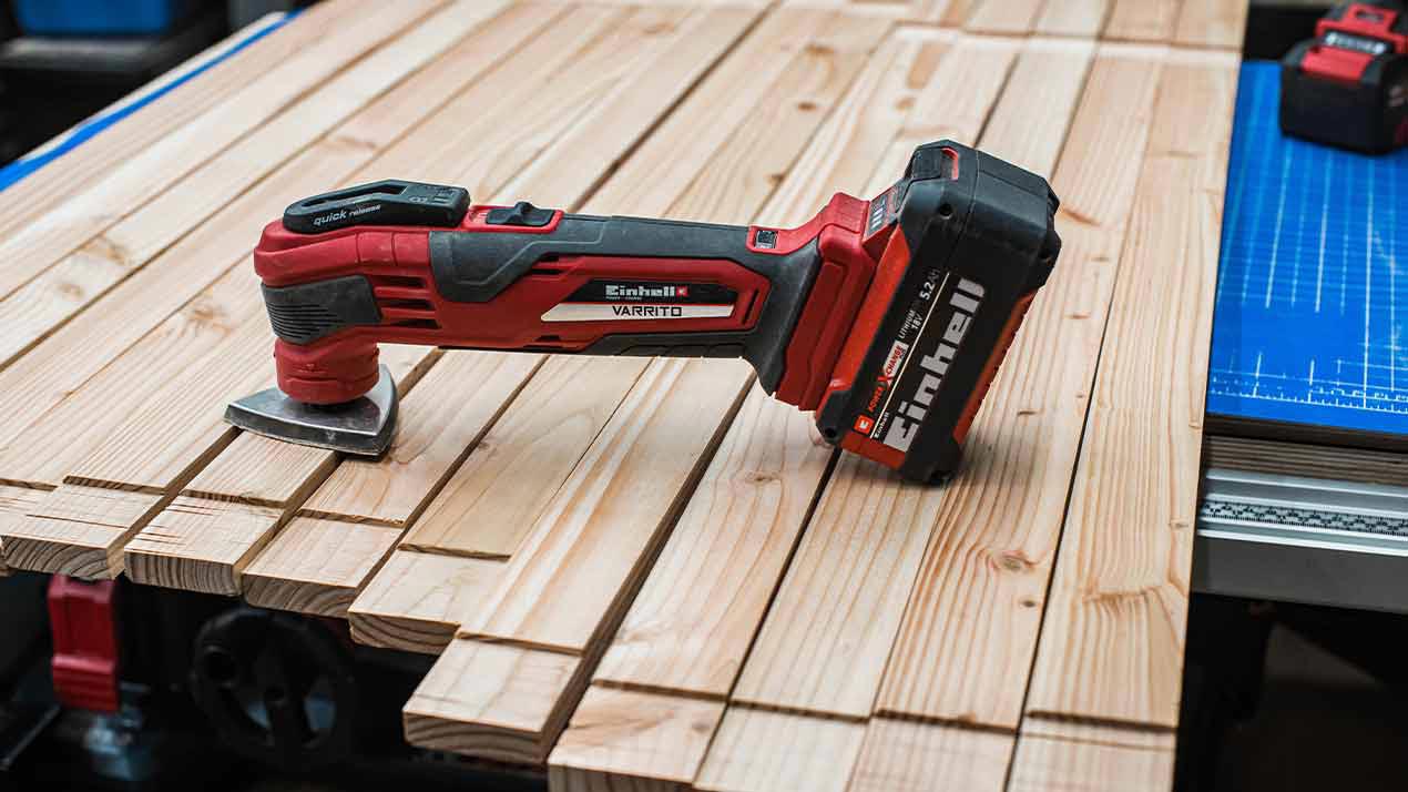 The cordless sander is lying on wooden boards and is ready for use