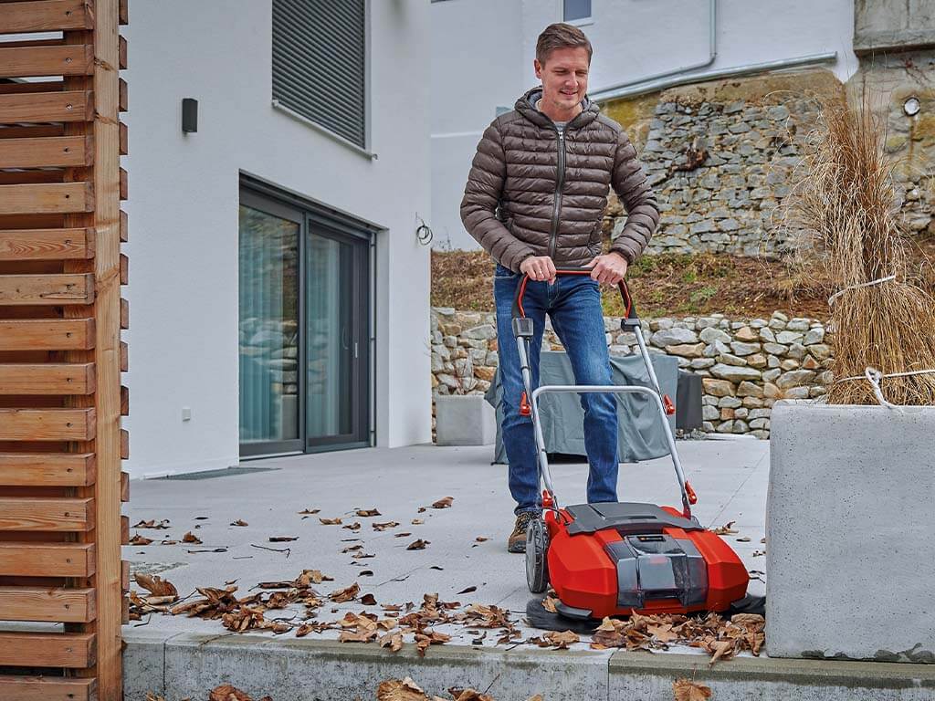 A man working with a Einhell push sweeper