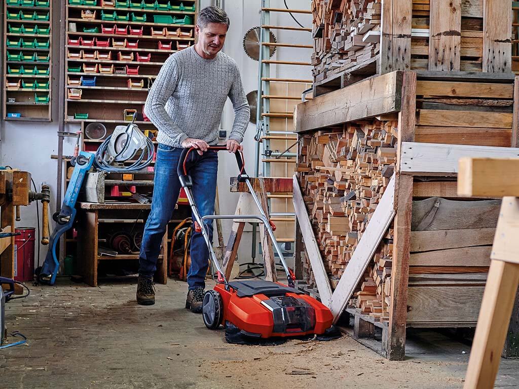 A man working with a Einhell push sweeper