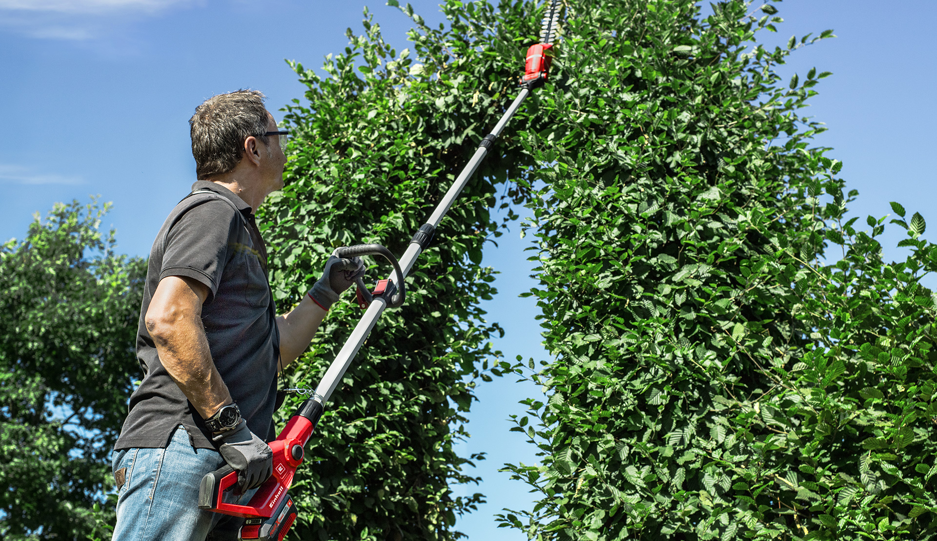 A man working with teleskop a hedge trimmer