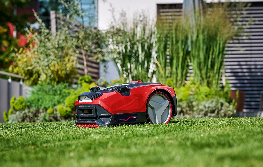 A robotic mower with camera and sensor technology is placed on the lawn in a garden.