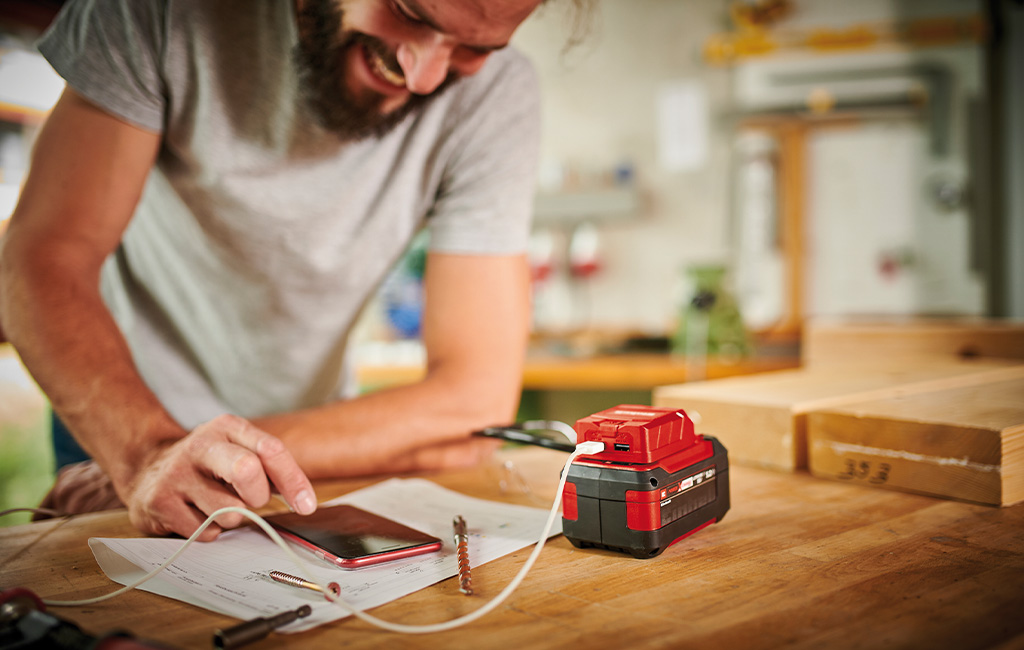 A man is using the einhell USB-battery-adapter to charge his phone