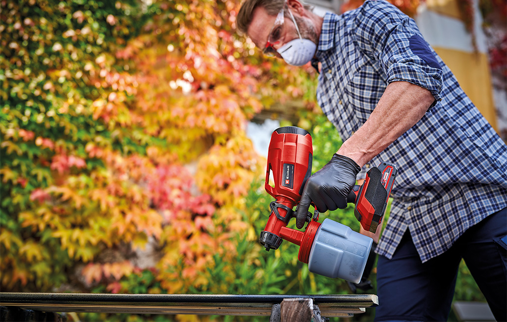 A man is spraying paint onto wood using the einhell spray gun