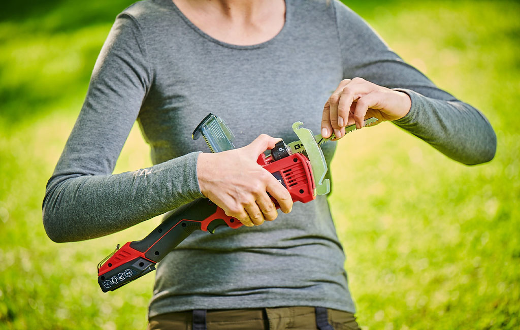 Woman changing the saw blade of a cordless pruning saw