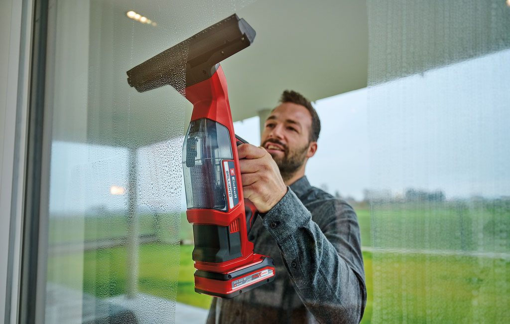 Man is cleaning window with Einhell cordless window cleaner BRILLIANTO