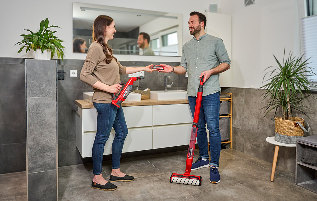 a woman and a man exchange an Einhell Power X-Change battery in a bathroom