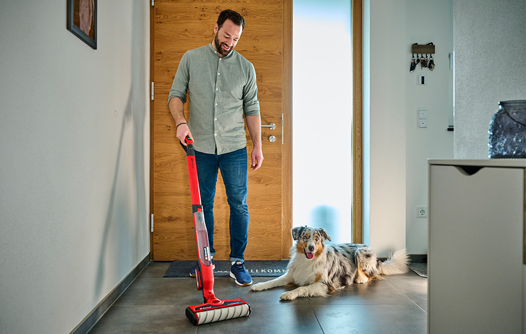 a man is cleaning the floor with the Einhell Cordless Hard Floor Cleaner CLEANEXXO