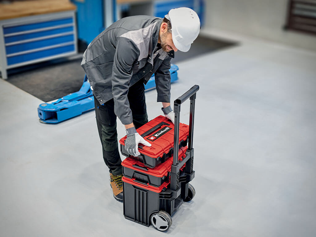 Un homme empile et connecte plusieurs mallettes Einhell E-Case.