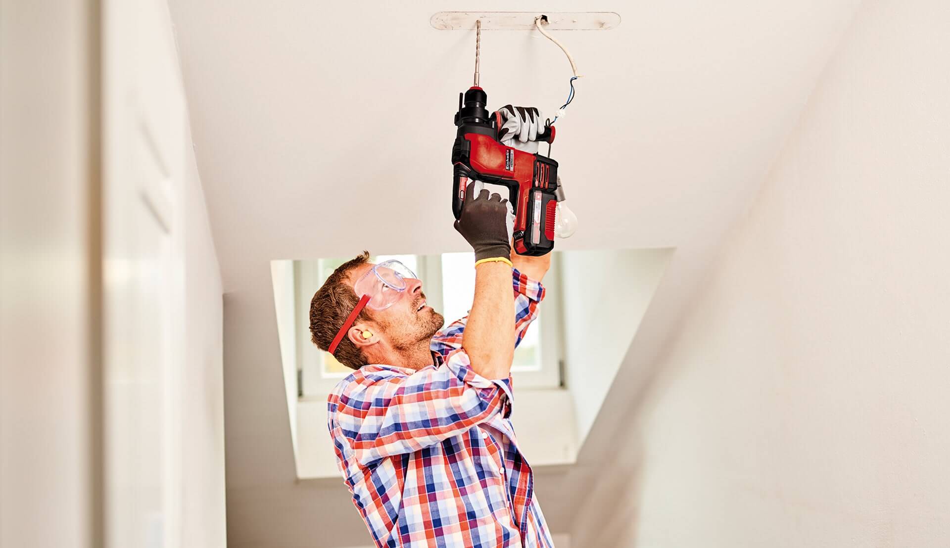 man using cordless rotary hammer in a house